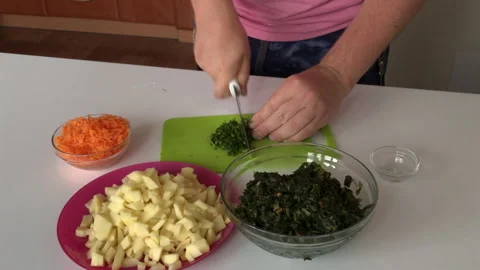 A man chops dill on a cutting board and puts it in a container. Nearby are po Stock Footage 136253449