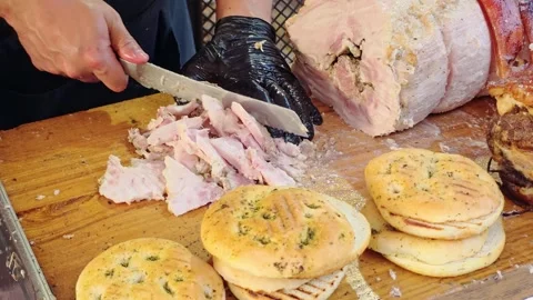 Man chops sliced roasted pork on a wooden board at a German food festival, .. Vídeo Stock 342747781
