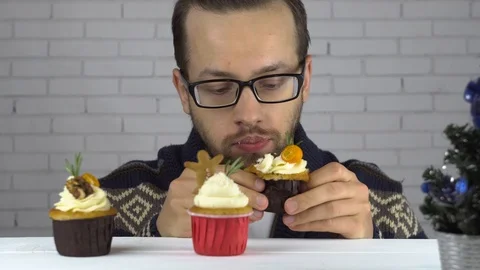 A man chose a cupcake and eats greedily 動画素材 99705846