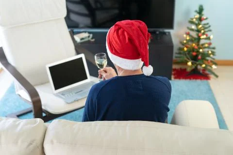 Man with Christmas hat toasting in front of the computer. Stock Photos