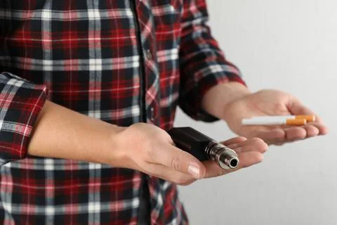 Man with cigarettes and vaping device on light background, closeup. Smoking a Stock Photos