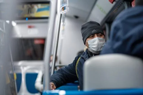 A man in a city bus wearing a protective medical mask. Stock Photos