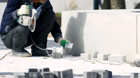 Man city worker checks place for cut paving slab placement Stock Footage 243298201