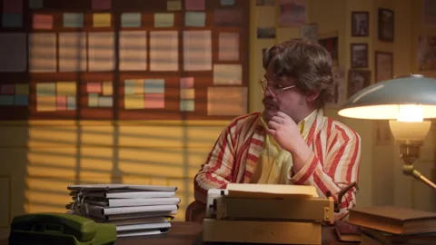 Man, clad in a bathrobe, sits at his desk in a retro office, tapping away at a Stock Footage 280109839