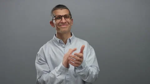 Man clapping wearing glasses and striped shirt against isolated grey wall b.. Stock Footage 314244242