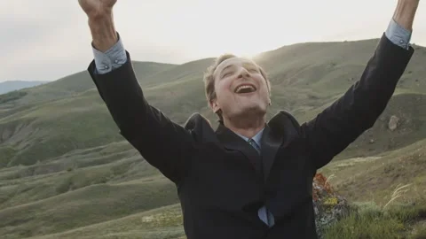 A man in a classic suit, against the backdrop of wild nature and the rays of the Stock Footage 258479003