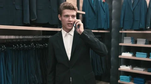 A man in a classic suit talking on a cell phone in shop Stock Footage 66428195