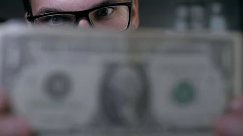 Man in classical clothes and glasses carefully examines a monetary Stock Footage 89366750