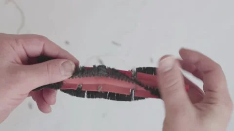 Man is cleaning automatic robot vacuum cleaner's brush Stock Footage 147041314