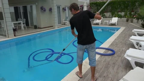 Man cleaning bottom of private pool with vacuum cleaner Video stock 133144272