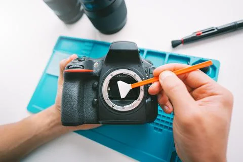 Man cleaning a camera matrix with cleaning swab. Photography equipment care Stock Photos