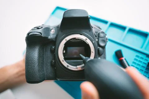 Man cleaning a camera matrix with dust blower. Photography equipment care Stock Photos