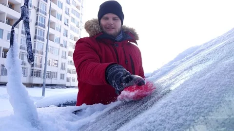 Man cleaning car windshield of ice with scrapper Video stock 149623236