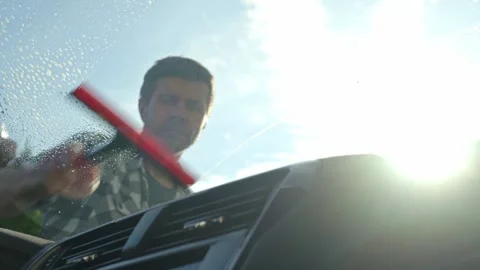 Man cleaning car windshield with squeegee from outside Stock Footage 308873562