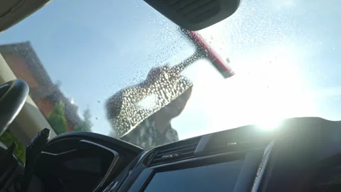 Man cleaning car windshield with squeegee from outside Stock Footage 309526388
