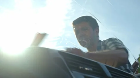 Man cleaning car windshield with squeegee from outside Stock Footage 310610071
