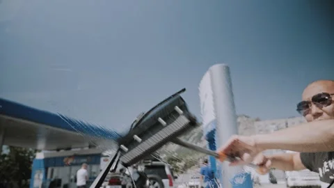 Man Cleaning Car Windshield with Squeegee Tool at Gas Station Service 動画素材 338226710