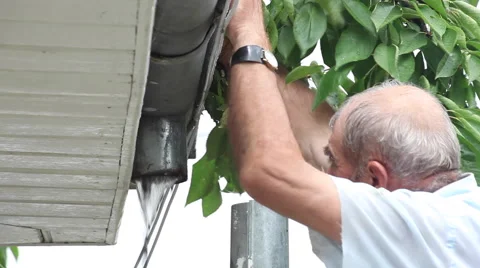 Man cleaning clogged gutter,connecting,fixing, downspout,drainpipe,flowing water Stock Footage 40670541