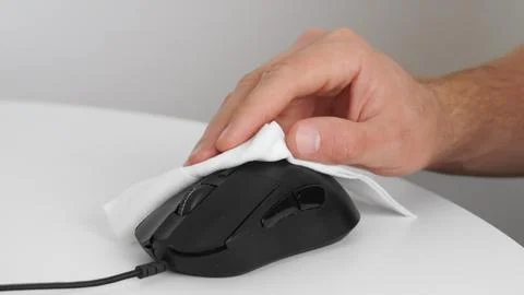 Man cleaning computer mouse with disinfecting wipe at white table indoors, .. Foto stock