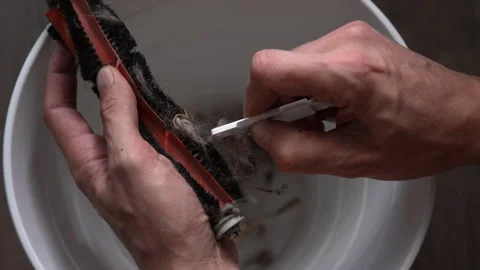 Man cleaning dirty robot vacuum cleaner brush roller. Hands using special tool Stock-Footage 342754391