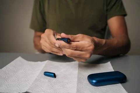 Man cleaning electronic cigarette emphasizing importance of hygiene and Stock Photos
