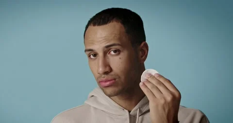 Man cleaning face with white pad. Handsome guy applying lotion with cotton pad Stock Footage 221995873