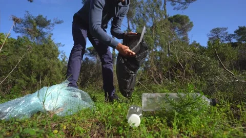 Man cleaning-up the forest of plastic garbage. Volunteer picking up a plastic Stock Footage 148400832