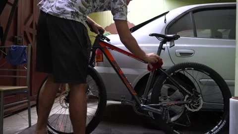 A man cleaning his bicycle with a rag in the garage of his house 库存影片 149208902