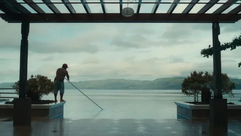 A man cleaning an infinity pool at dawn Stockbeeldmateriaal 334380406