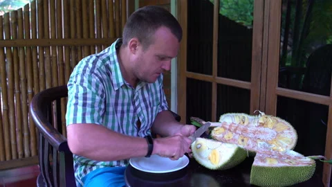 A man is cleaning a jackfruit on the terrace Stock Footage 91882500