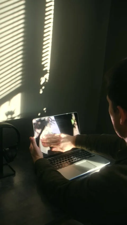 Man cleaning a laptop screen at a desk with a white cloth Stock Footage 337831233