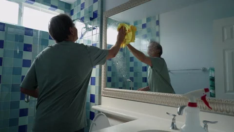 Man cleaning large bathroom mirror Stockbeeldmateriaal 286943226