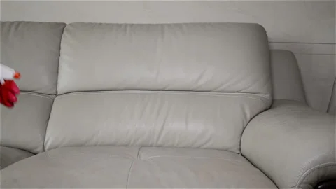Man cleaning leather sofa at home with wet towel Stock Footage 100800041