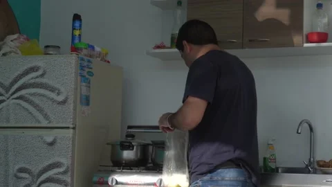 A man cleaning the leftovers from a pot in the kitchen in the morning in 4k Video stock 155817364