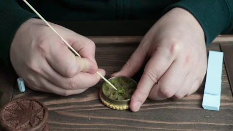 Man cleaning marijuana grinder from grinded cannabis with wooden chopstick. Stock Footage 128070729