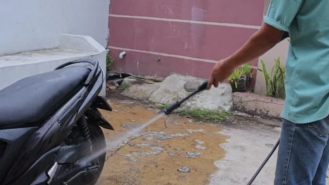 Man cleaning motorbike using power washer stream during weekend routine outdoors Stock Footage 336736121