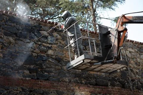 Man cleaning old dirty wall with high pressure water jet Stock Photos