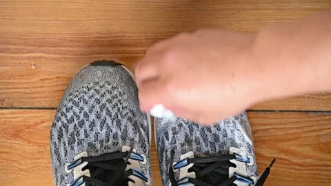Man cleaning pair of shoes with a soapy cleaning sponge Stock Footage 255637668
