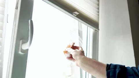 Man cleaning a plastic window frame with an orange sponge in the room Vídeo Stock 340159434