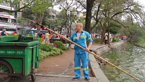 Man Cleaning Pond with Long Net 動画素材 292871439