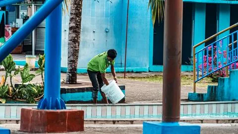 A man is cleaning a pool with a bucket Stock Photos