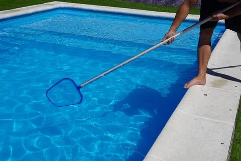 Man cleaning the pool surface with pool cleaner mesh or skimmer Foto stock