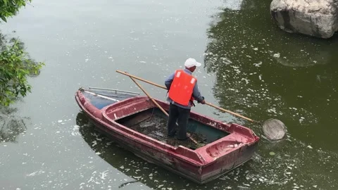 Man cleaning river surface with net from small boat. Video stock 341586033