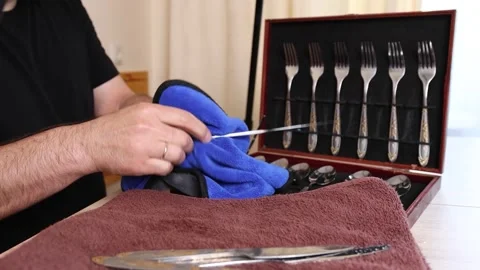 Man cleaning a silver knife with cloth, polishing cutlery set at home, househ Stock Footage 315213076