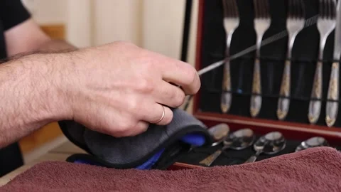 Man cleaning a silver knife with cloth, polishing cutlery set at home, househ Stock Footage 315213361