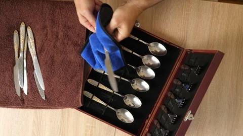 Man cleaning a silver knife with cloth, polishing cutlery set at home, househ Stock Footage 315213825