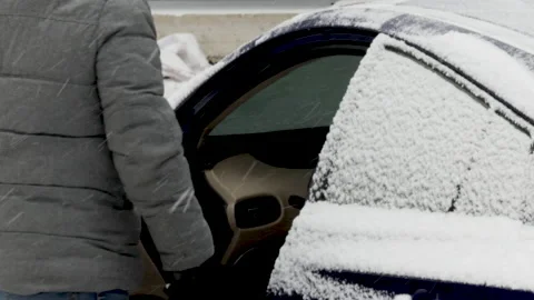 Man is cleaning snow from car with a red color brush. Video stock 167912446