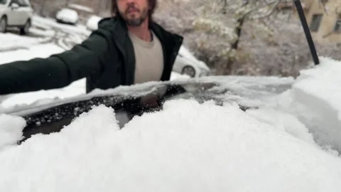 Man cleaning snow from car windshield outdoors, winter weather and vehicle Stock Footage 337110661