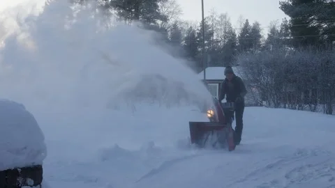 Man cleaning snow with snow blower machine at home, foggy frosty air on eve.. Stock Footage 264773741