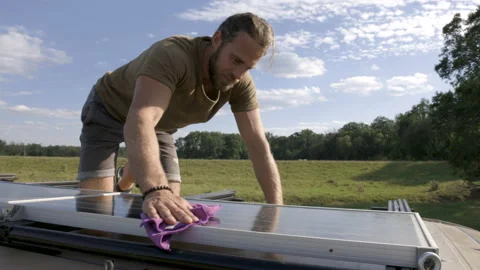 Man cleaning the solar panel on top of a camper van Video stock 225888420